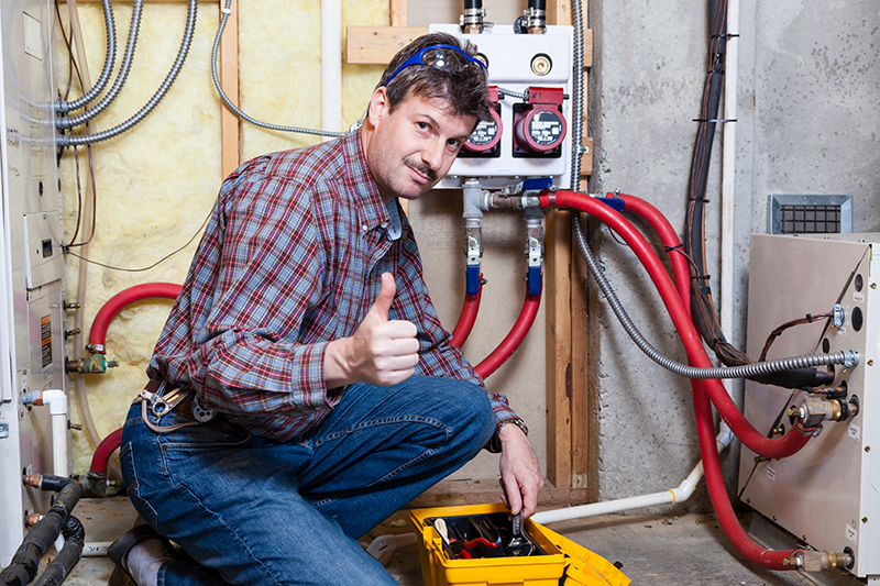 A handy-man examines a furnace. Why Is the Furnace Pilot Light Going Out?