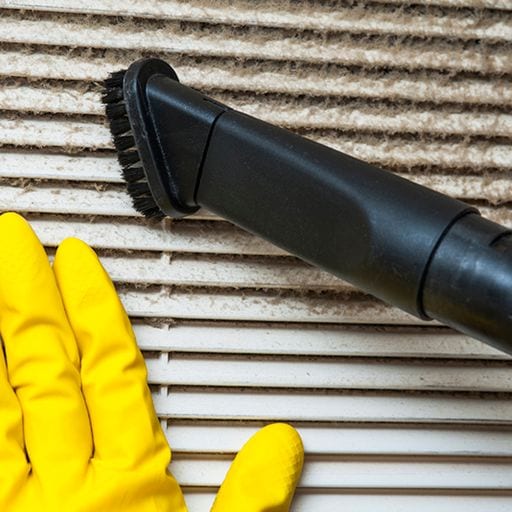 A person with a rubber glove cleans an air vent. 5 Tips to Improve Your Indoor Air Quality This Fall.